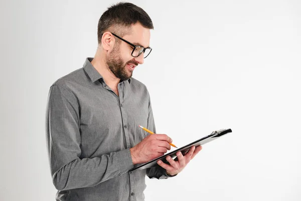 Knappe zakenman holding Klembord notities schrijven. — Stockfoto