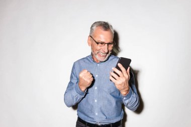 Smartphone kullanarak ve kazanan jest yapmak mutlu adam