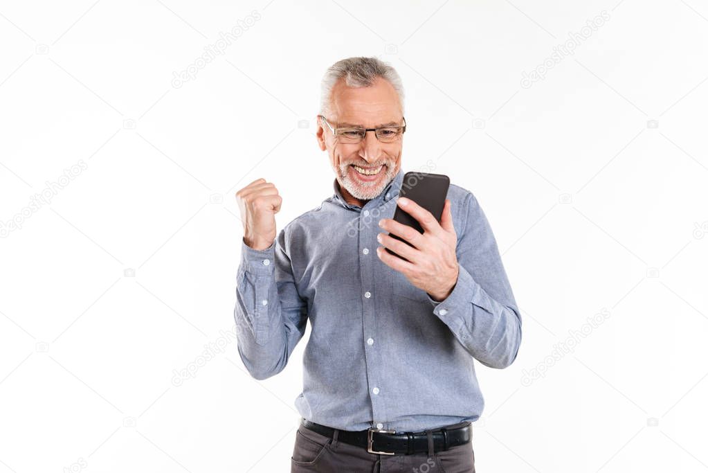 Happy man using smartphone and making winner gesture