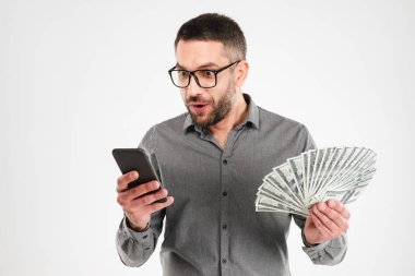 Heyecanlı işadamı cep telefonuyla para tutan.