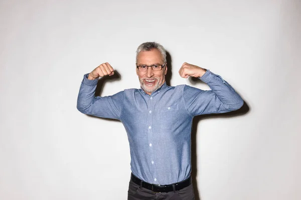 Vecchio uomo sorridente mostrando i suoi bicipiti muscolari isolati su bianco — Foto Stock