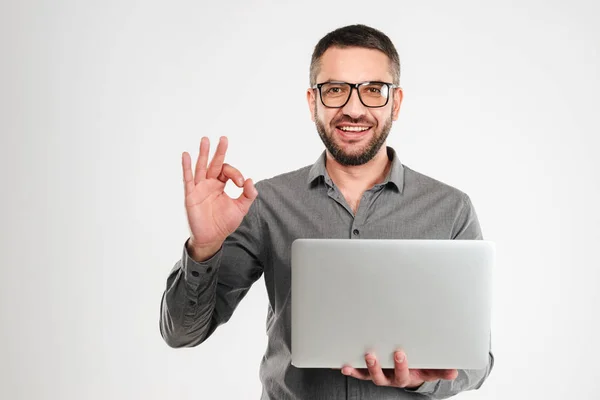 Hombre de negocios alegre usando el ordenador portátil que muestra gesto bien . — Foto de Stock
