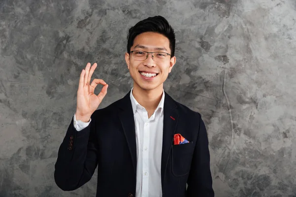 Portrait of a cheerful young asian man dressed in suit