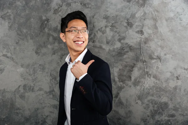 Portrait of a cheerful young asian man dressed in suit — Stock Photo, Image
