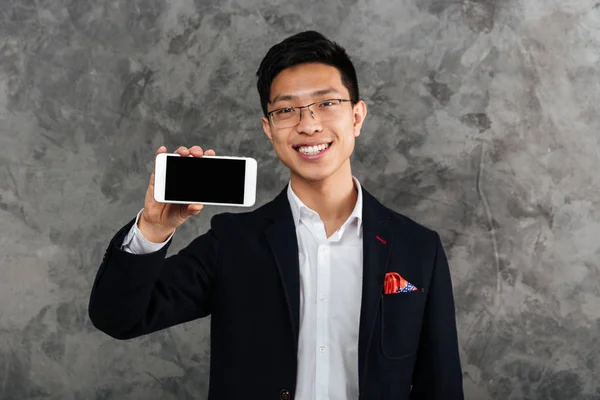 Portrait of a laughing young asian man dressed in suit — Stock Photo, Image