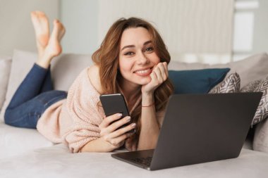 Cep telefonu kullaranarak gülümseyen bir genç kadın portresi