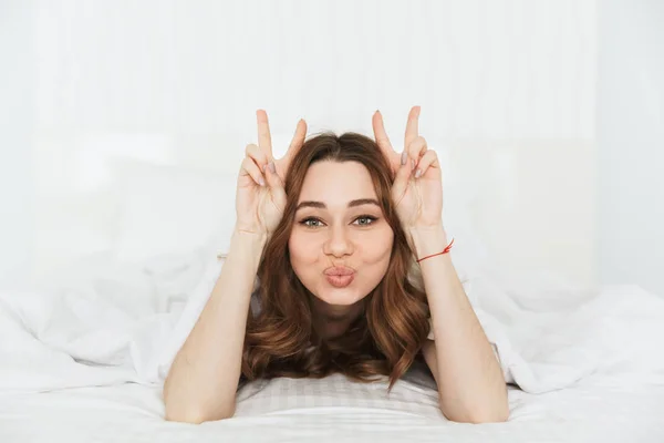 Battaniyenin altında yatakta yatan genç komik bir kadın portresi — Stok fotoğraf