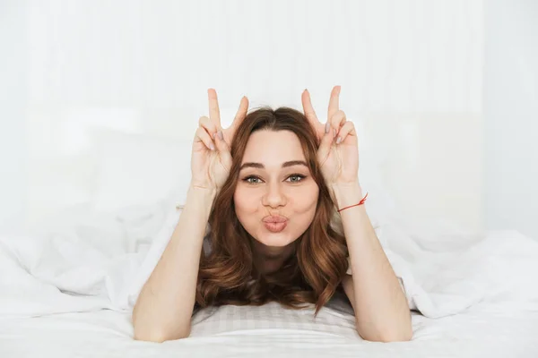 Portrait d'une drôle de jeune femme couchée au lit sous la couverture — Photo