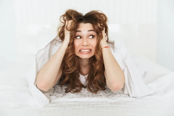 Retrato de una joven frustrada acostada en la cama — Foto de Stock