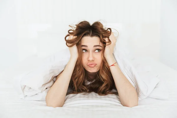 Nachdenkliche junge Frau liegt im Bett — Stockfoto