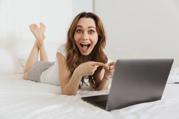 Portret van een enthousiast jonge vrouw in bed liggen — Stockfoto
