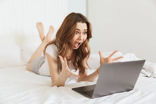 Portrait of a shocked young woman lying in bed at home — Stock Photo, Image