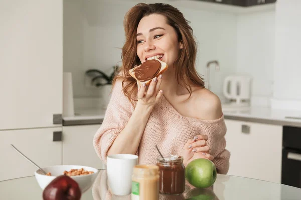 Portret van een tevreden jonge vrouw lekker ontbijten — Stockfoto