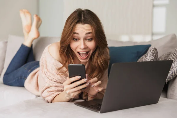 Portret van een enthousiast jonge vrouw met behulp van mobiele telefoon — Stockfoto