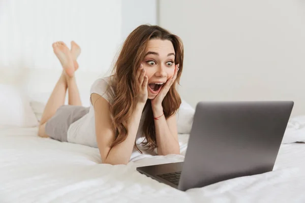 Portrait of an excited young woman lying in bed at home Stock Picture