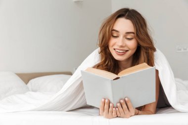 Neşeli kadın yatakta beyaz battaniye altında yatakta yalan portresi