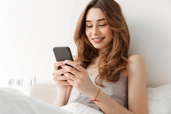 Retrato de una joven mujer alegre descansando en la cama después de dormir con —  Fotos de Stock