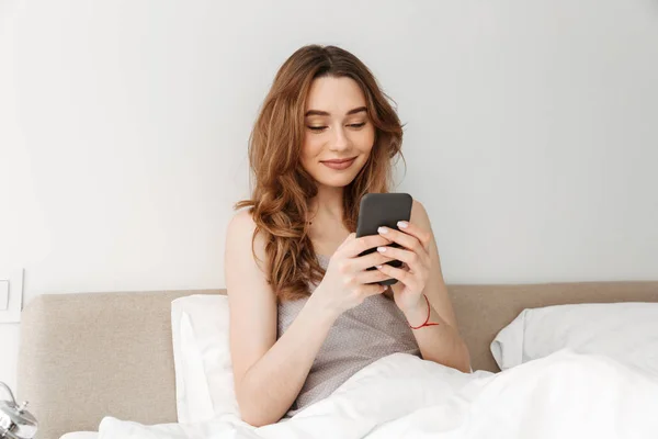 Picture of pleased woman with natural beauty lying in bed with w — Stock Photo, Image