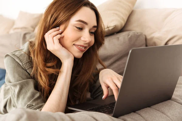 Image of smiling attractive woman with brown hair lying on sofa — Stock Photo, Image