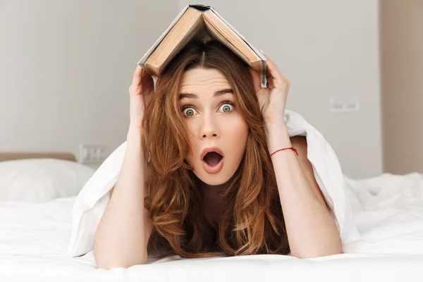 Foto de mujer excitada 20s acostada en la cama debajo de una manta blanca en b — Foto de Stock