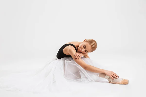 Beautiful young woman ballerina sitting on floor — Stock Photo, Image