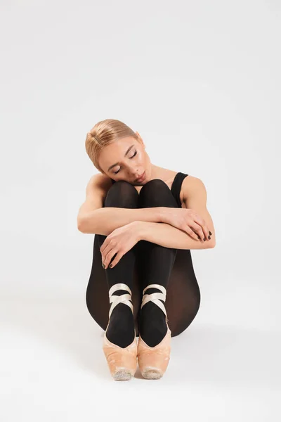 Pretty young woman ballerina sitting on floor — Stock Photo, Image