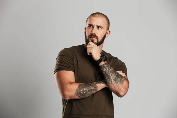 Portrait of manly bald guy with tattoo on his arms looking aside