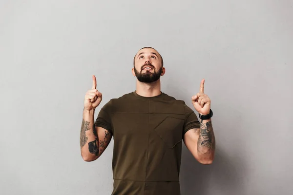Imagen de hombre barbudo con tatuajes en brazos mirando hacia arriba con po — Foto de Stock