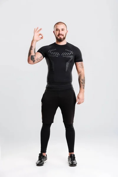 Retrato de cuerpo entero del hombre tatuado fuerte en ropa deportiva negra — Foto de Stock