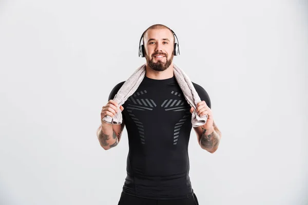 Foto de hombre musculoso escuchando música a través de auriculares y mantenga — Foto de Stock