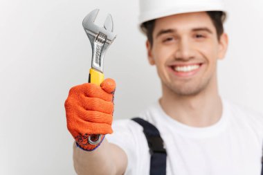 İngiliz anahtarı gösterilen kameraya gülümseyen erkek Oluşturucu