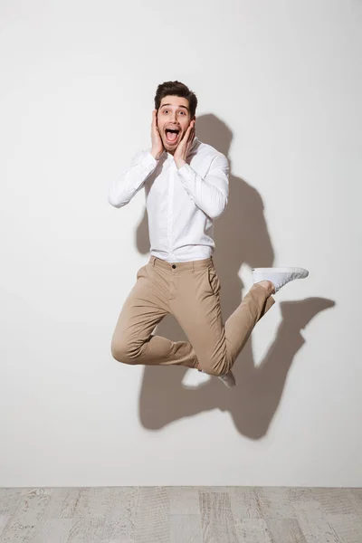 Full length photo of surprised guy in shirt and trousers jumping — Stock Photo, Image