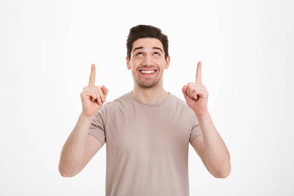 Positive brunette man 30s wearing beige t-shirt gesturing finger