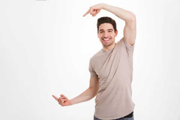 Junger glücklicher Mann um die 30 in beigem T-Shirt, der Freude ausdrückt, wenn er — Stockfoto