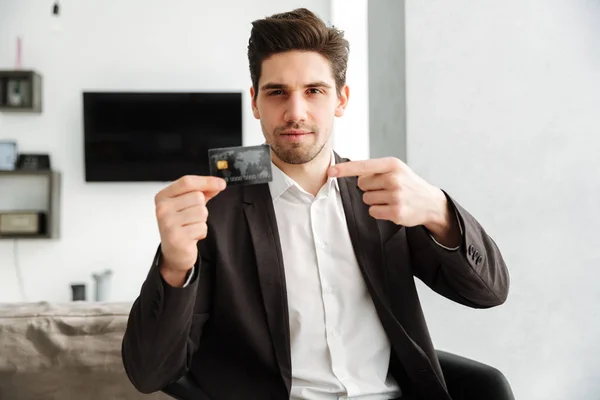 Jovem empresário sério mostrando cartão de crédito apontando . — Fotografia de Stock