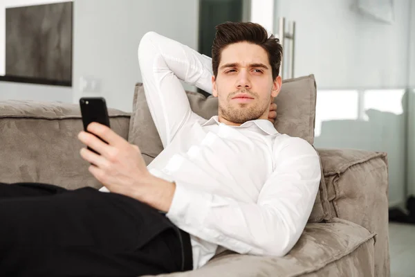 Concentrado joven hombre de negocios en casa se encuentra en el sofá — Foto de Stock