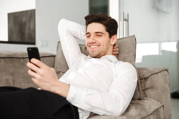 Веселий молодий бізнесмен вдома лежить на дивані — стокове фото
