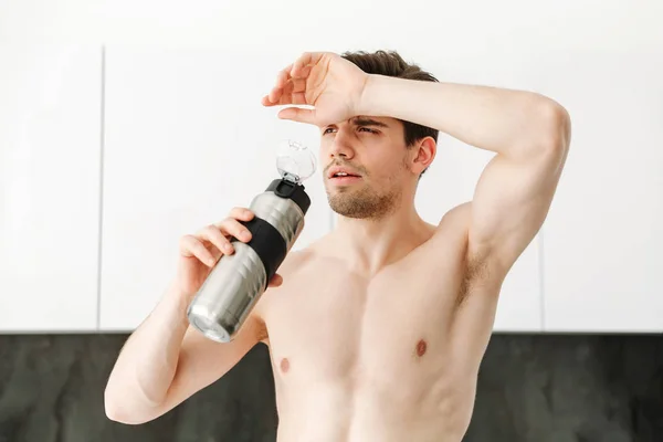 Серьезный голый спортсмен, стоящий на кухне — стоковое фото