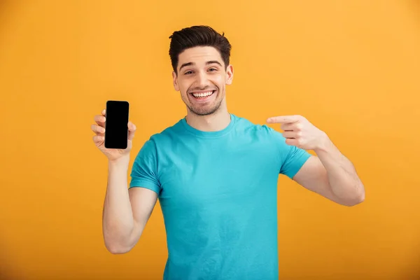 Retrato de um jovem sorridente em camiseta apontando o dedo — Fotografia de Stock