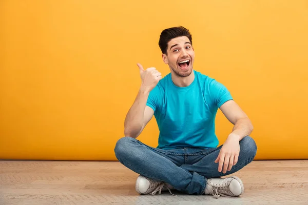 Retrato de um jovem alegre apontando o dedo — Fotografia de Stock