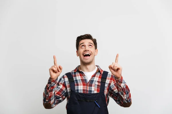 Счастливый мужчина строитель указывая двумя указательными пальцами и глядя вверх — стоковое фото