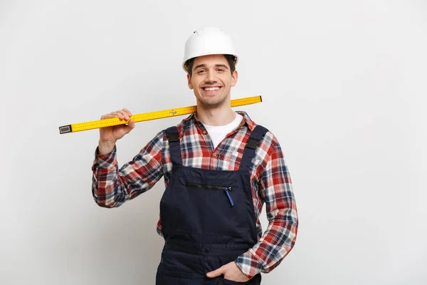 Costruttore maschio sorridente in casco protettivo tenendo strumento livello — Foto Stock