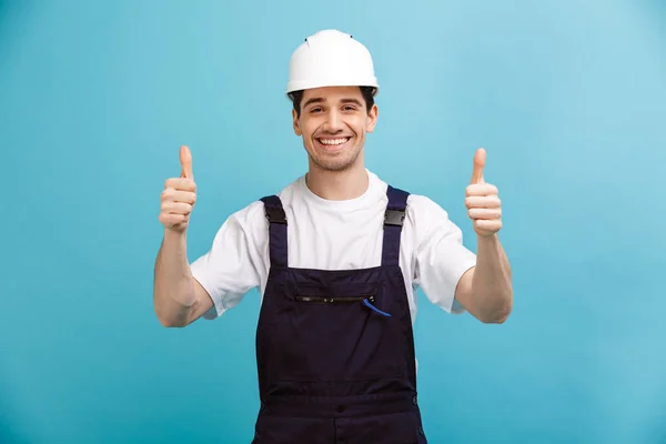 Constructor masculino sonriente en casco protector mostrando pulgares hacia arriba — Foto de Stock