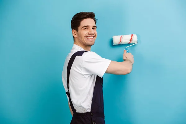 Sidovy av glad builder målning vägg med paint rulle — Stockfoto
