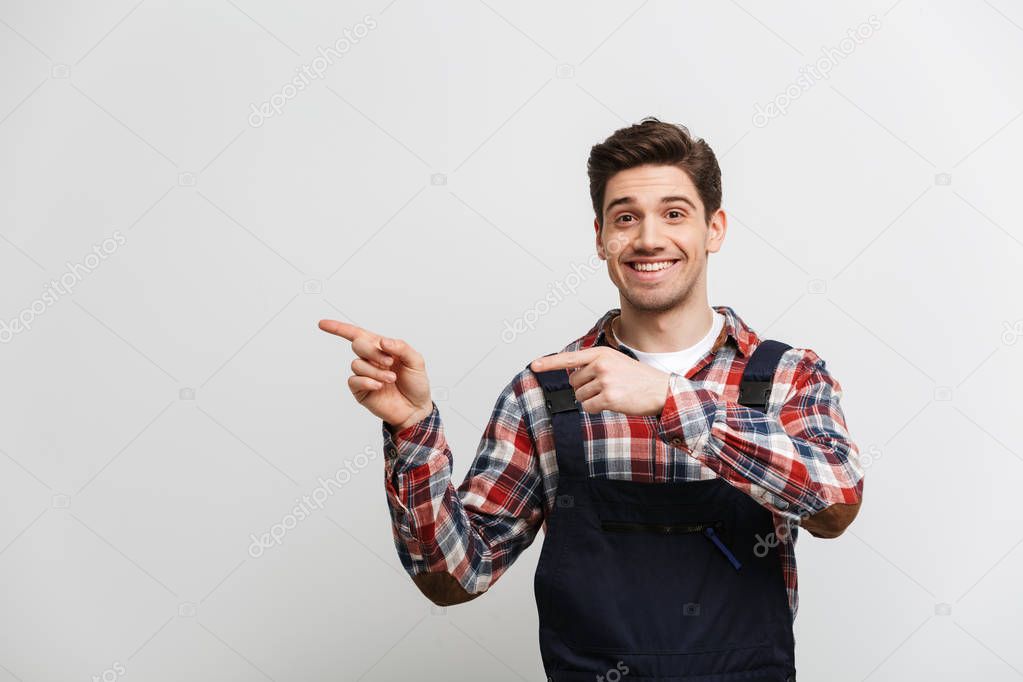 Happy male builder pointing away with two forefingers
