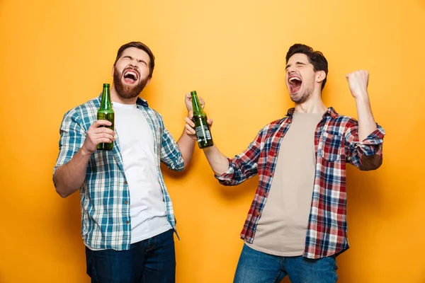 Retrato de dos jóvenes alegres sosteniendo botellas de cerveza — Foto de Stock