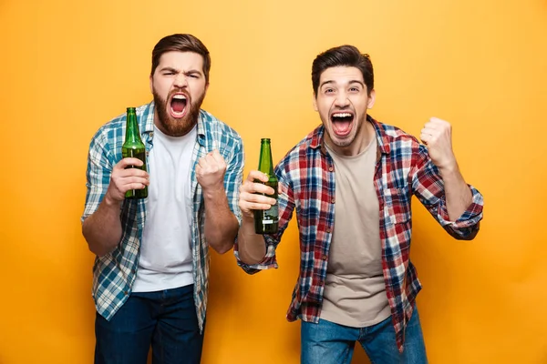 Retrato de dos jóvenes excitados sosteniendo botellas de cerveza — Foto de Stock