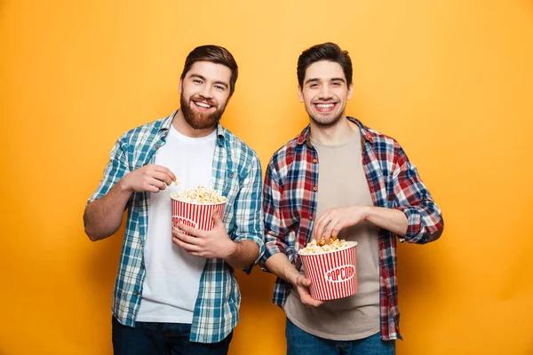 Porträtt av en två glada unga män äta popcorn — Stockfoto