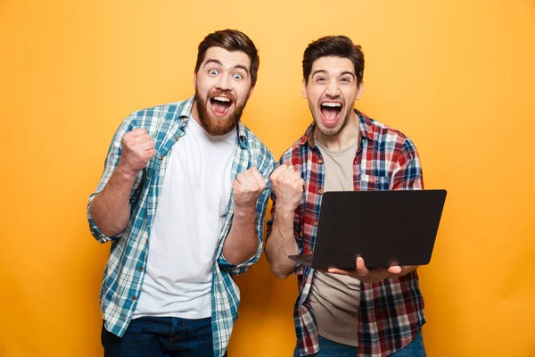 Retrato de dois jovens felizes segurando laptop — Fotografia de Stock