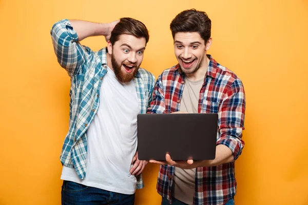 Porträtt av två glada unga män hålla laptop — Stockfoto